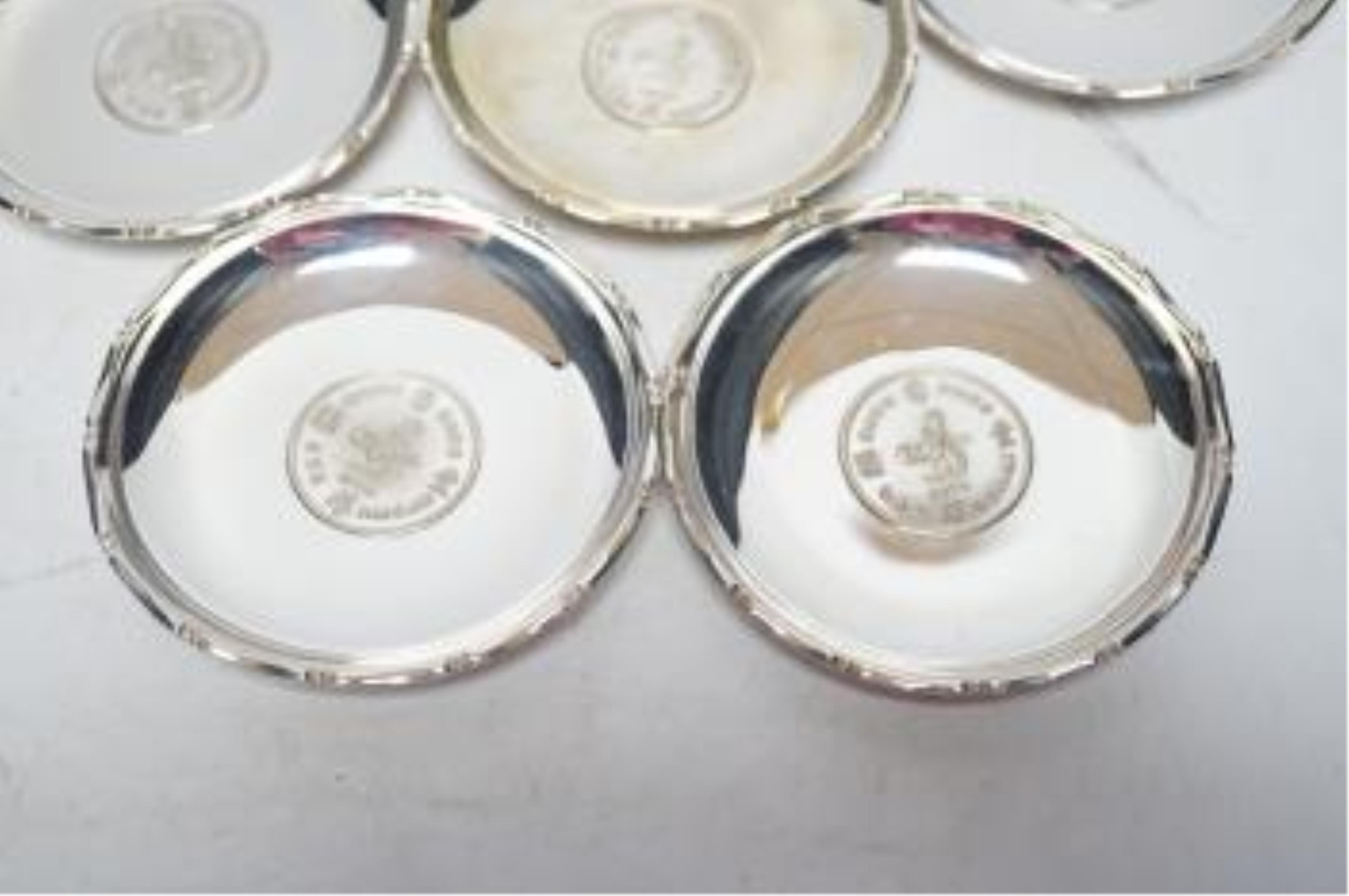 A set of seven Hong Kong sterling small dishes with inset coin, signed 'Sammy', diameter 86mm, gross weight 10.2oz. Good condition.